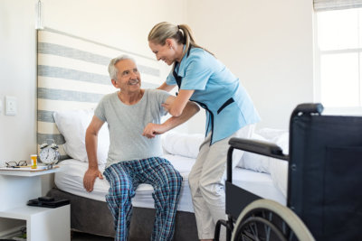 a nurse assisting a senior man to stand