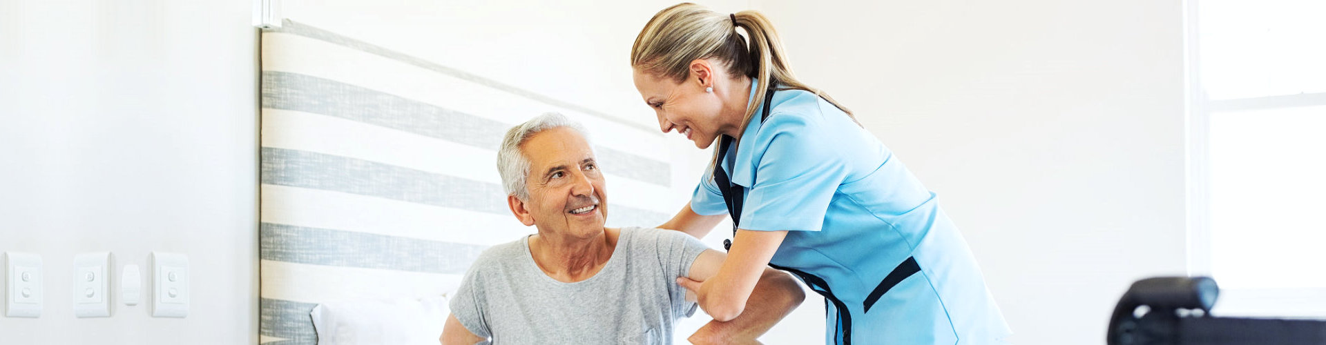 a nurse assisting a senior man to stand